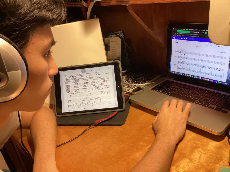 Composing the Piece Through the Parts — Senior Sebastian Lennox reviews the completed segments of his music composition. Notes for the piece are lined up to the right, on his iPad; on his computer, his composing software is set up. Through the headphones, flute, viola, and harp play.
