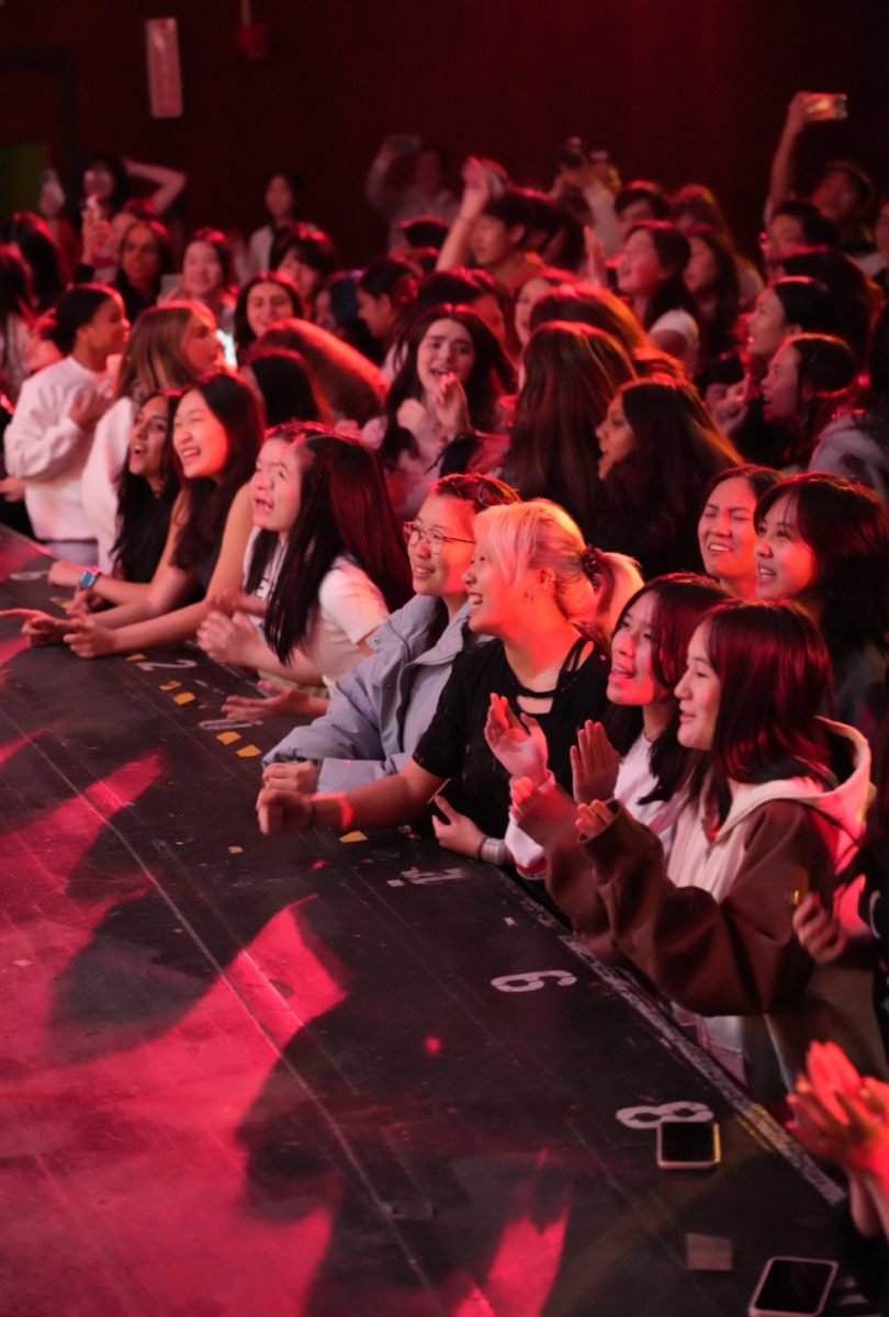 Dancing in Dark Red—Spotlights on the stage illuminate smiling faces nestled near the stage center. Students and faculty, singing and swaying along with the music, enjoy the company of their peers while marveling at the talented band performances. 