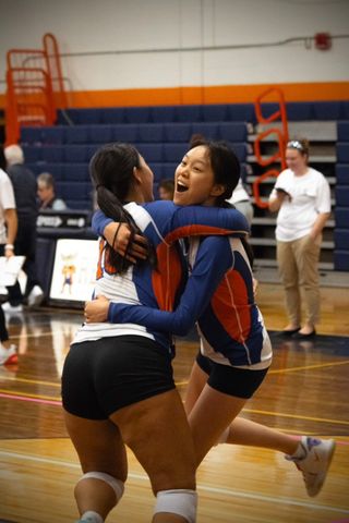Friendship Flourishes in Triumph—Junior Kary Wong (right) and Senior Jill Wang (left) share a heartfelt hug after clinching a crucial point.