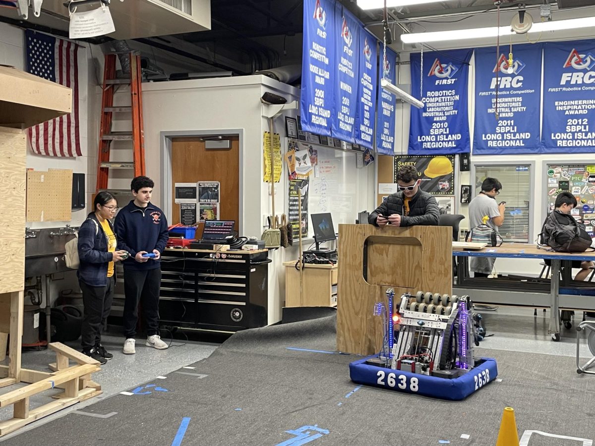 Rebel Robotics Team 2638 trains its robot and its members—Junior Michael Melamed teaches a sophomore Robotics member how to maneuver the robot while programmers code in the back.