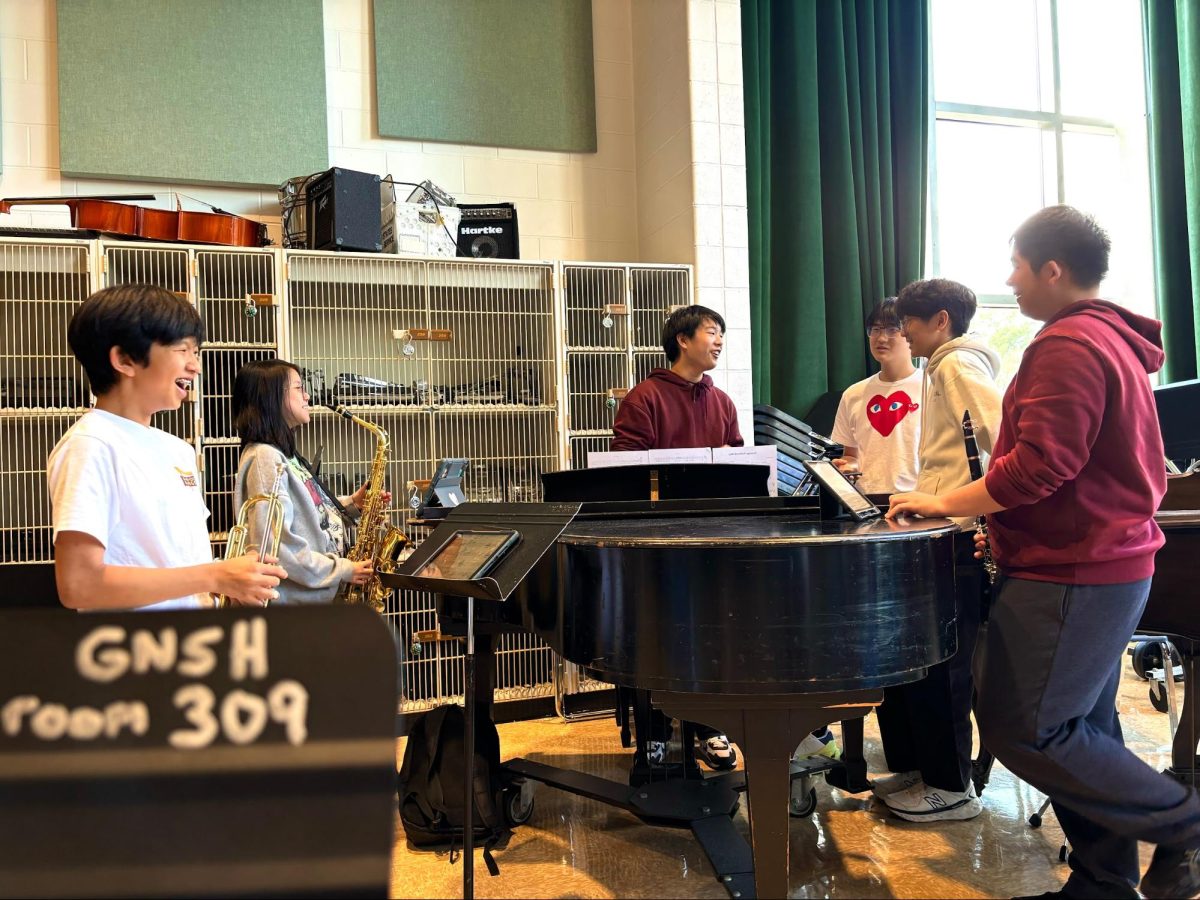 Taking Things From the Start—Ethan Lee, Kimberly Chan, Henry Xu, Ivan Chen, Colin Huh, and Avery Zhou troubleshoot their rendition of Laufey’s “From the Start” in preparation for Coffee House. Because Mr. Schwartz is busy with opera callbacks, Henry conducts the band in his absence. His bandmates laugh as he attempts to conduct with one hand and play piano with the other.