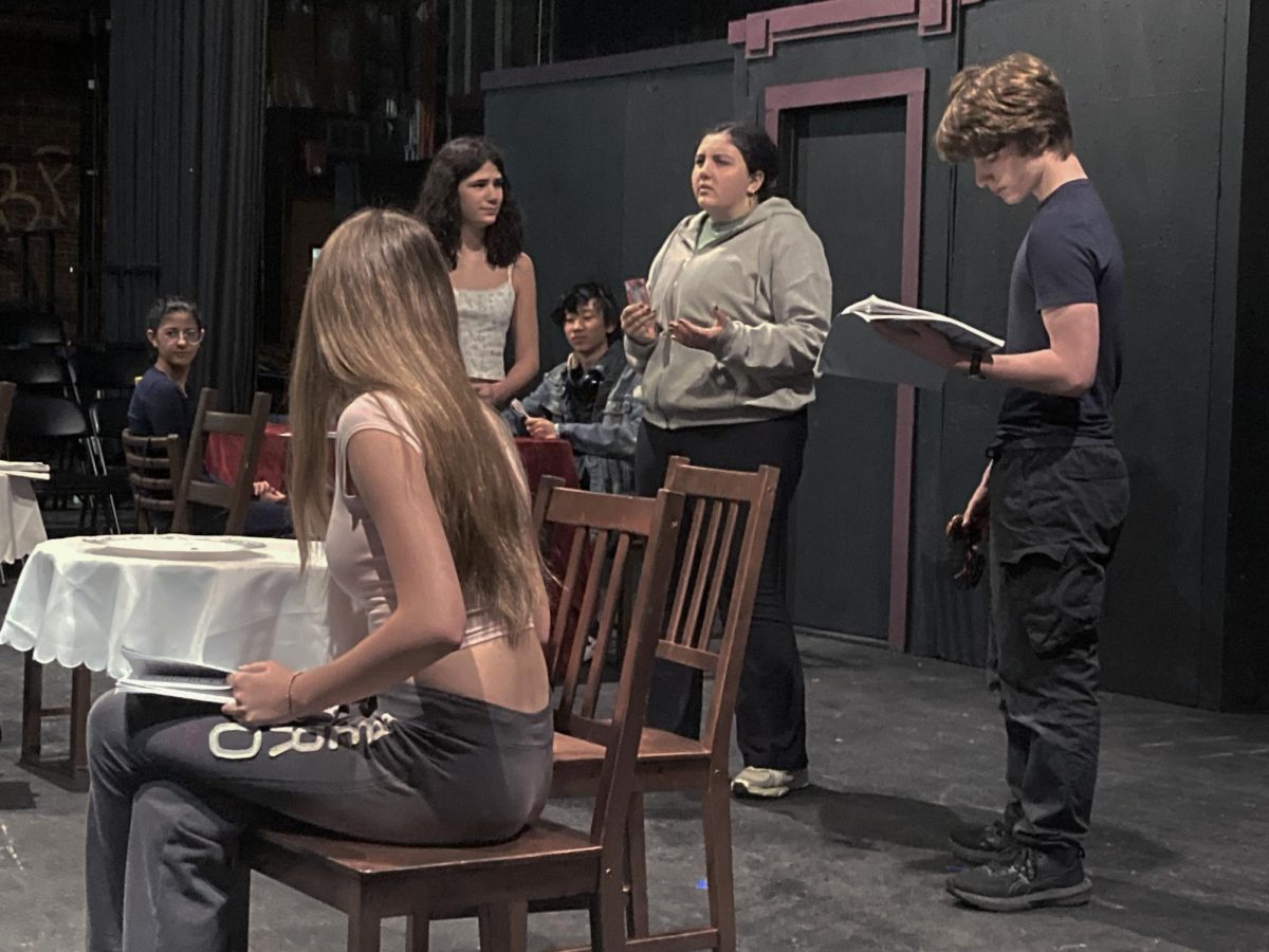 Remembrance and Remorse — Sadie Baker (Chantelle Delson) watches the memory of her younger self (Sofia Gurtman) at her Papa’s (Emma Condello’s) hospital bedside as the Narrator (Sam Bernstein) silently watches. Family is an important theme in Sadie Baker, especially how their desires can go against your own. The play uses this complexity to explore Sadie’s inner conflict: wanting to stay and care for her Papa vs. his desires for her to pursue her dreams. Her decision set off the events of the play.
